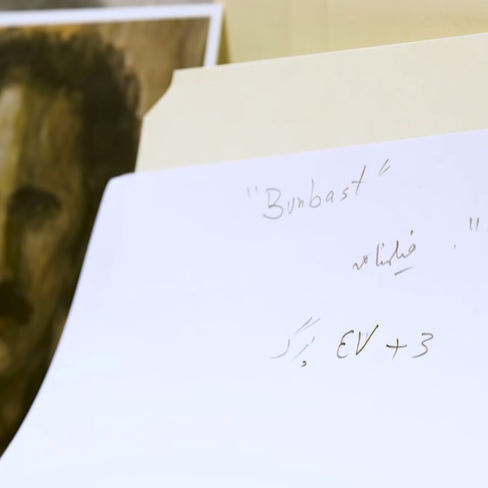 Image of Houshang Golshiri next to handwritten document in Persian from the archive