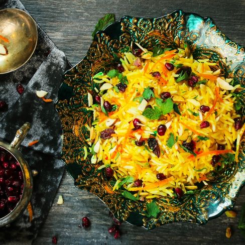 Display of decorative Persian food dishes on table: rice in bowl, barberries in small bowl